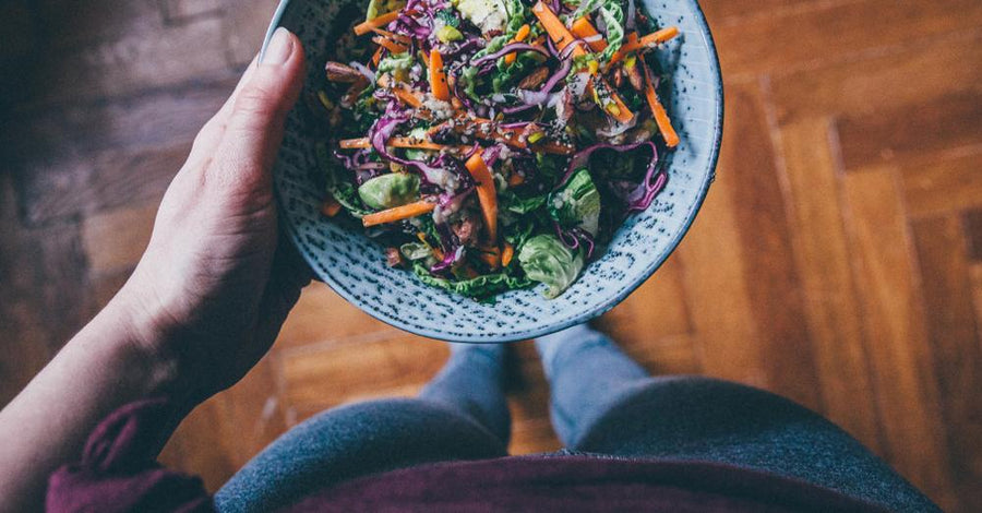 Woman holding mixed greens salad in bowl