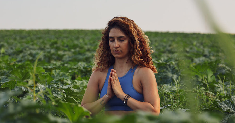 Woman meditating in a field of tall plants