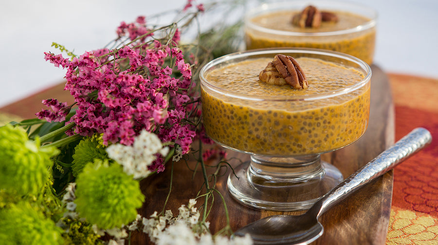 Pumpkin Chia Pudding in dish with flowers behind 