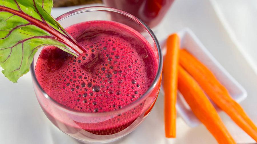 Root Juice in glass with carrots on side