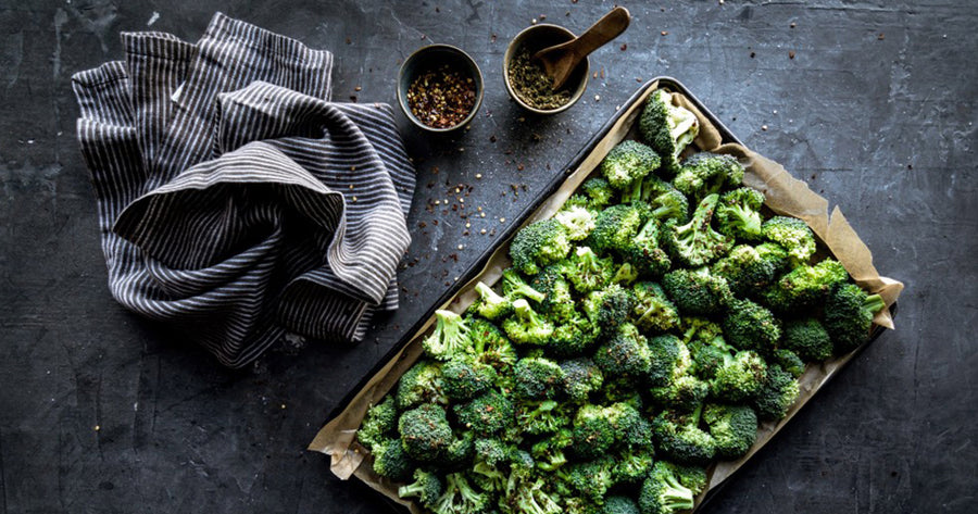 Tray of broccoli next to spices and kitchen towel