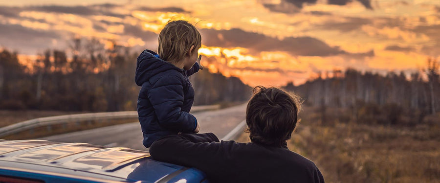 father and son enjoying sunset on roadtrip