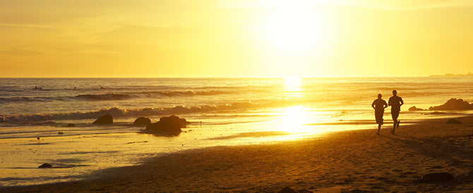 Couple running on beach with sun shining